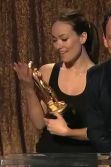 Olivia Wilde puts a trophy in her mouth at an awards show